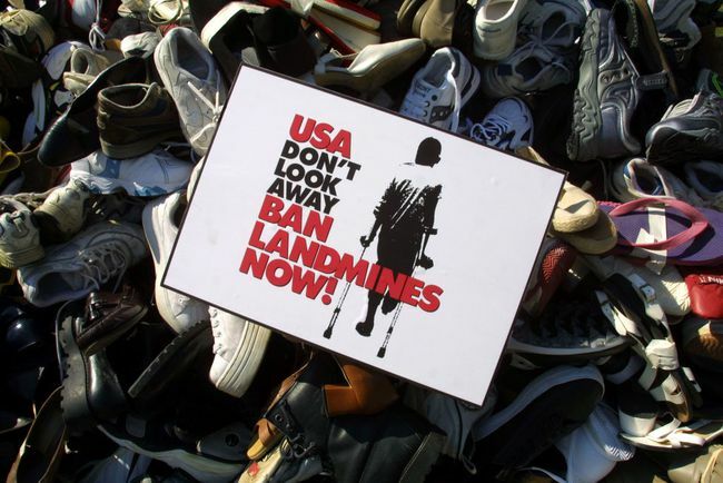 Un panneau d'interdiction des mines terrestres est placé sur une pyramide empilée par des chaussures recueillies au cours des derniers mois par la campagne américaine pour interdire les mines terrestres.