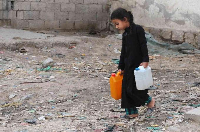 Une petite fille porte des jerrycans remplis d'eau propre à partir d'une pompe de bienfaisance au cours d'une crise d'eau potable au Yémen