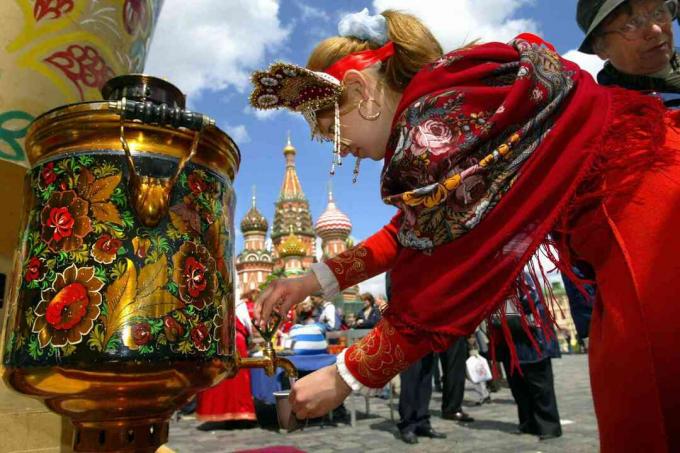 Fille russe portant un vêtement traditionnel verse de l'eau du samovar