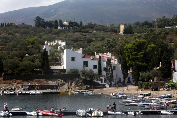 maison asymétrique blanche nichée dans le rivage surplombant de nombreux petits bateaux