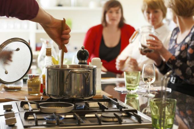 Remuer une casserole sur une cuisinière dans un îlot de cuisine permet une interaction avec les convives.