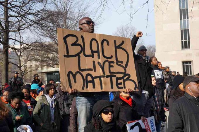 Un homme protestant contre la mort de Michael Brown, Eric Garner et Tamir Rice affiche un Black Lives Matter à Washington DC.
