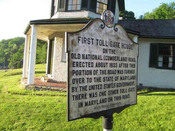 Maison de péage et marqueur historique sur la route nationale par une journée ensoleillée.