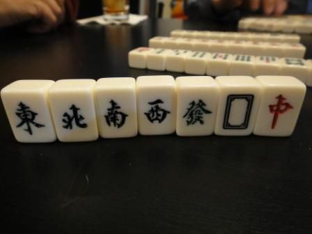 Les tuiles des vents et des dragons dans un ensemble de Mahjong debout sur une table.