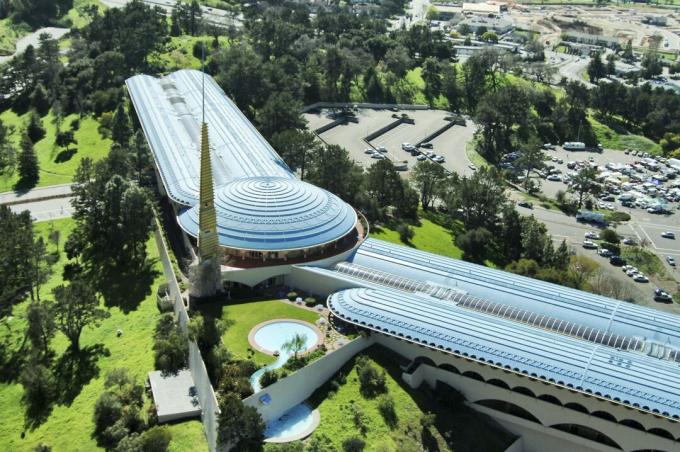Vue aérienne d'un vaste bâtiment ailé de chaque côté d'un dôme rond, bas, horizontal, organique à la terre