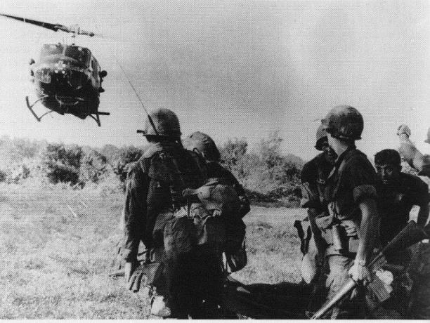 Hélicoptère UH-1 Huey atterrissant près d'un groupe de soldats.