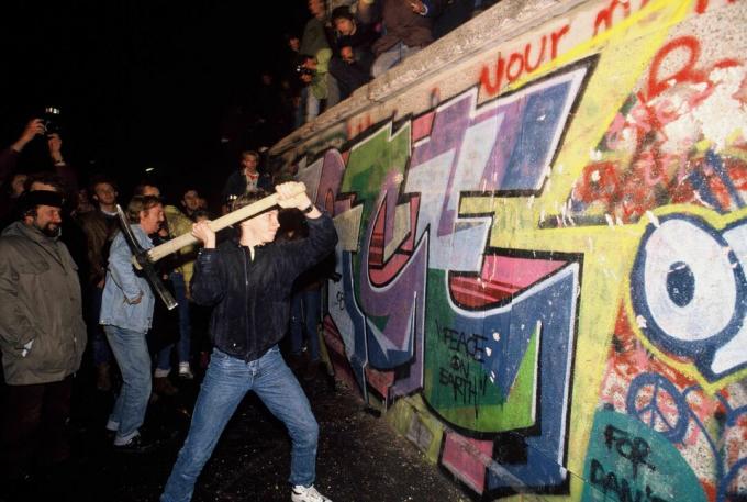 Un homme attaque le mur de Berlin avec une pioche dans la nuit du 9 novembre 1989