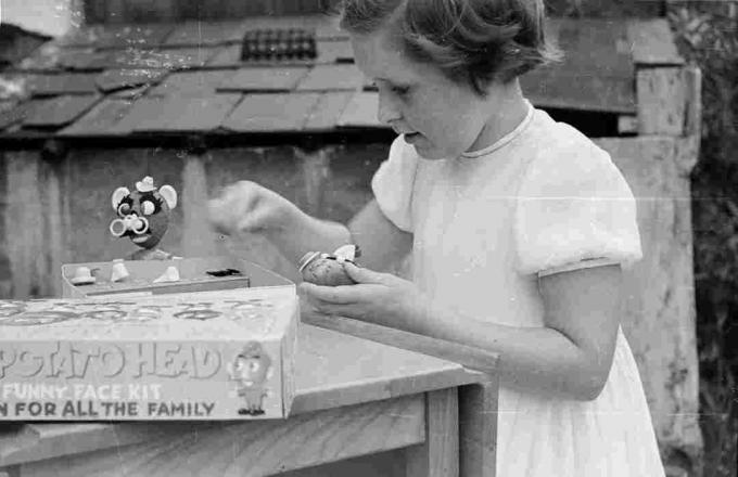 Enfant jouant avec M. Potato Head à table à l'extérieur.