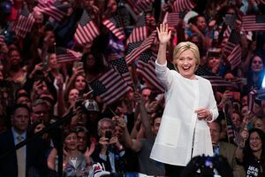 Hillary Clinton ondule devant une foule de personnes agitant des drapeaux américains