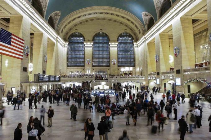 très grande salle, plafond incurvé avec puits de lumière clerestory, grandes fenêtres cintrées à une extrémité, des centaines de personnes debout sur le sol en marbre