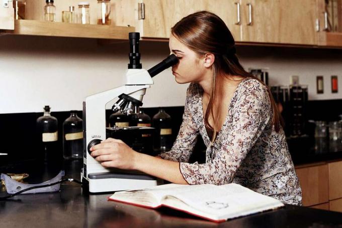 Adolescente (14-16) à l'aide de microscopes en classe de laboratoire scientifique