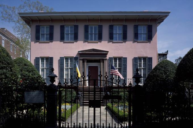 Maison victorienne de style italianisant, cinq fenêtres à volets au deuxième étage, portail en fonte à l'avant, murs de briques en stuc lisse d'une teinte rougeâtre