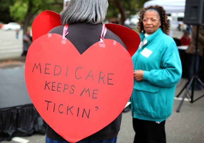 Femme portant une pancarte en forme de cœur indiquant " Medicare Keeps Me Ticking"