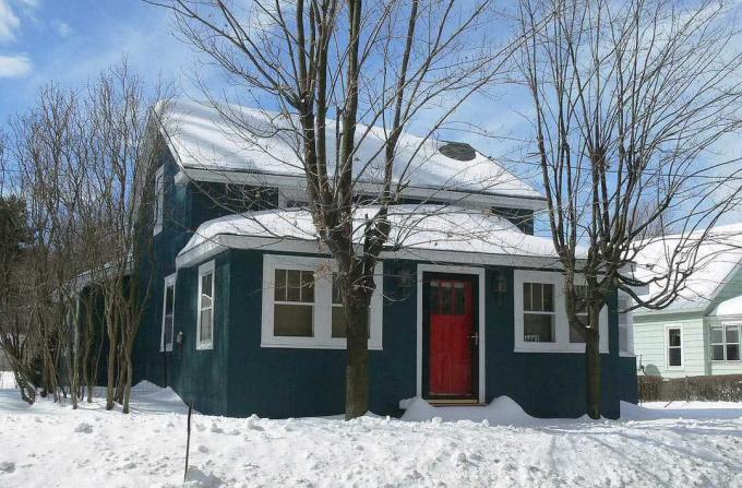 Une porte rouge vif est une caractéristique traditionnelle de nombreuses maisons. Cette maison de ferme est peinte d'une riche nuance de gris presque noire.