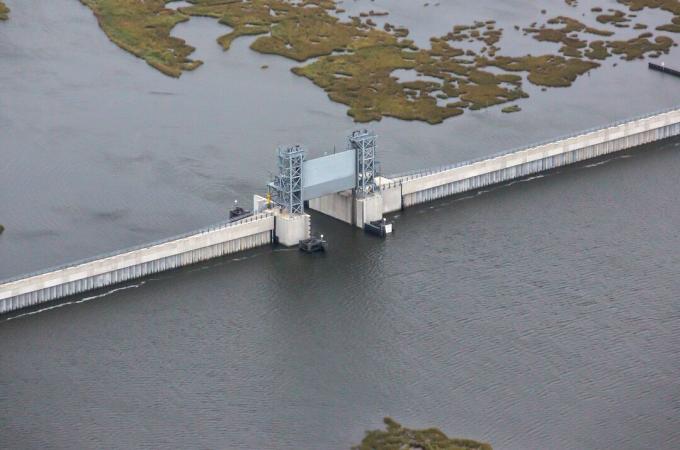 une porte verticale ouverte dans un mur de béton, de l'eau de chaque côté du mur