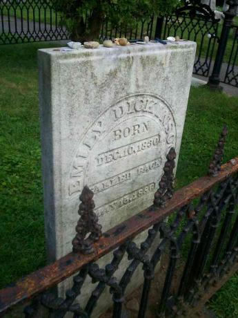 La pierre tombale d'Emily Dickinson derrière une porte en fer