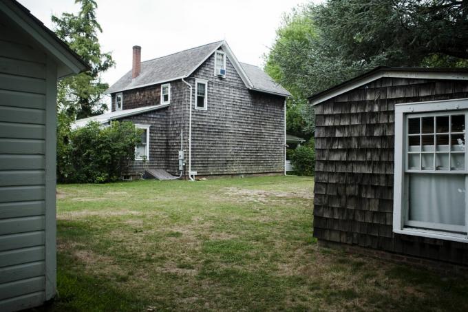 regardant entre les bâtiments en bardeaux à une maison à pignon à deux étages en bardeaux