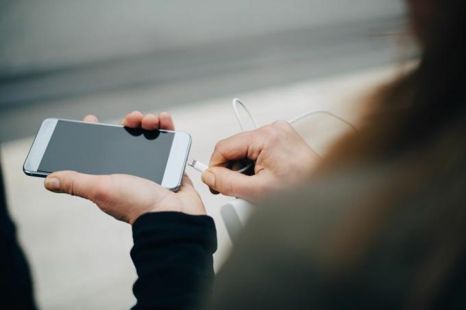 Une femme d'affaires insérant un câble USB dans un smartphone