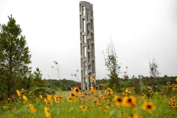 haut et mince clocher en pierre dans un champ de fleurs