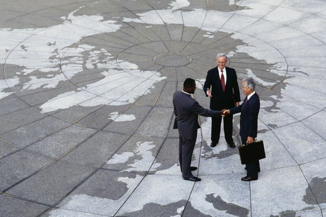  Régionalisme économique: hommes d'affaires se serrant la main sur la carte du globe.