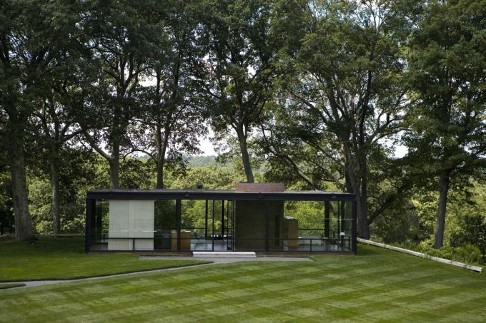 Vue lointaine de la maison en verre au milieu des bois