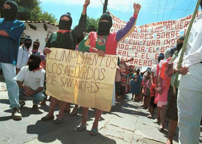 Deux femmes tiennent une pancarte exhortant le gouvernement à se conformer aux accords de San Andrés