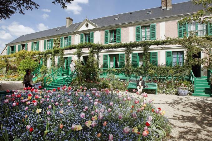 maison à deux étages orientée horizontalement, avec portique et fronton central, et volets et escaliers vert clair