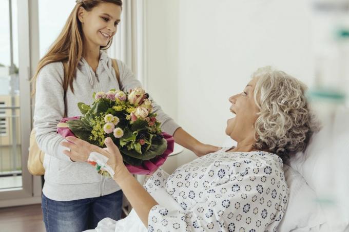 Petite-fille en visite à grand-mère à l'hôpital, apportant un bouquet de fleurs