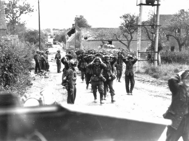 Des soldats allemands marchant dans une rue avec les mains sur la tête pour se rendre.